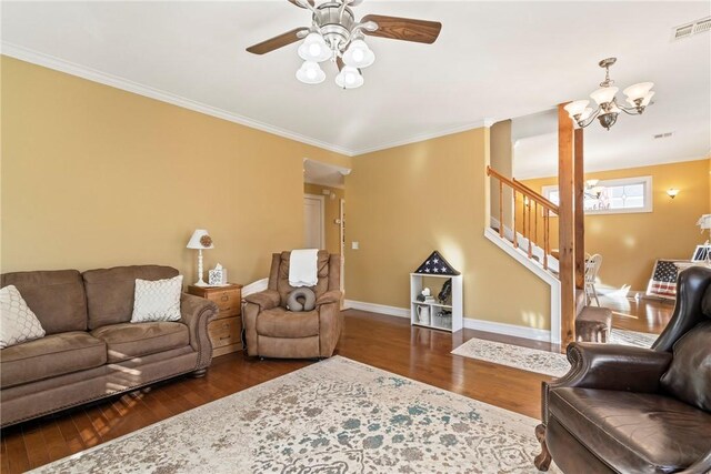 living room with ceiling fan with notable chandelier, dark wood-type flooring, and ornamental molding