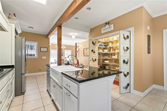 kitchen featuring white cabinetry, crown molding, a center island with sink, light tile patterned floors, and stainless steel appliances