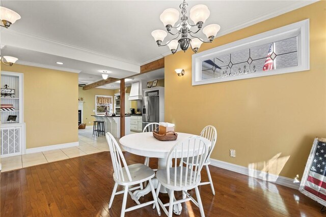 dining area with crown molding, an inviting chandelier, and light hardwood / wood-style floors