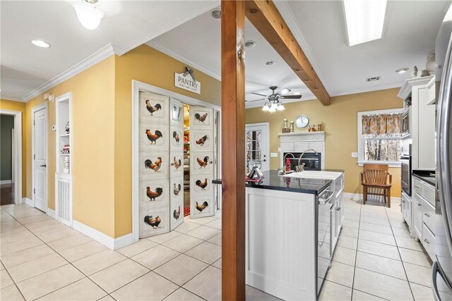 kitchen with light tile patterned flooring, crown molding, white cabinets, and a kitchen breakfast bar