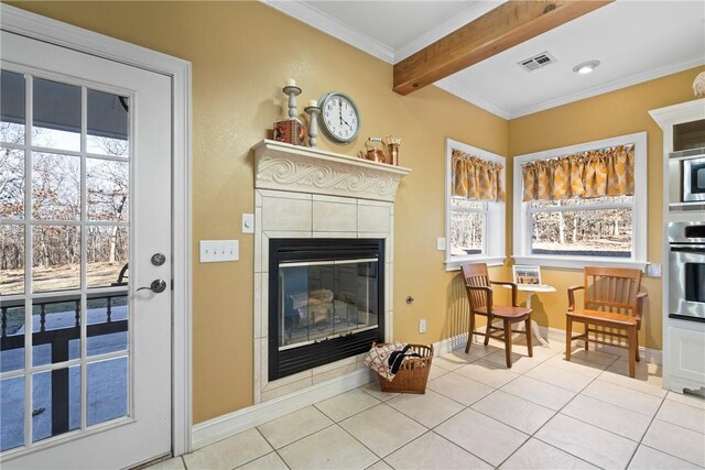 living area featuring beamed ceiling, a tile fireplace, light tile patterned flooring, and crown molding