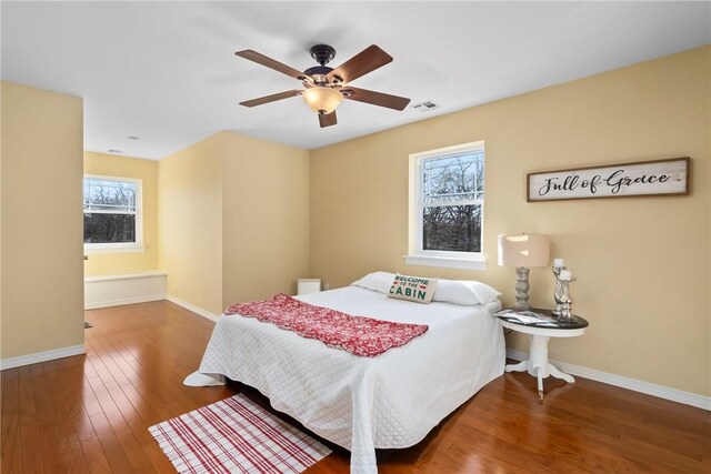 bedroom featuring hardwood / wood-style flooring, ceiling fan, and multiple windows