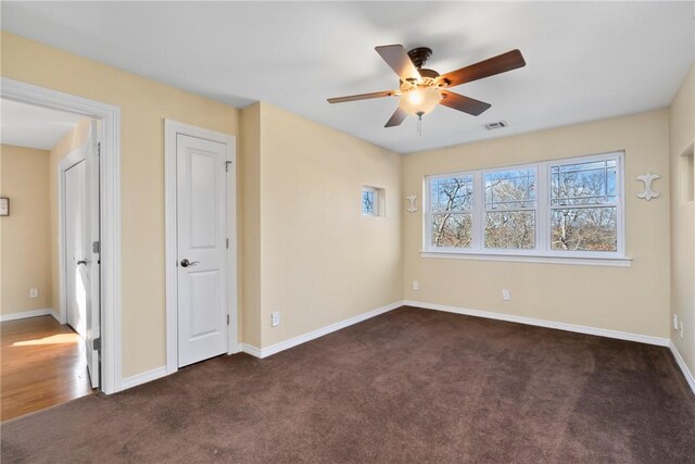 spare room featuring dark colored carpet and ceiling fan