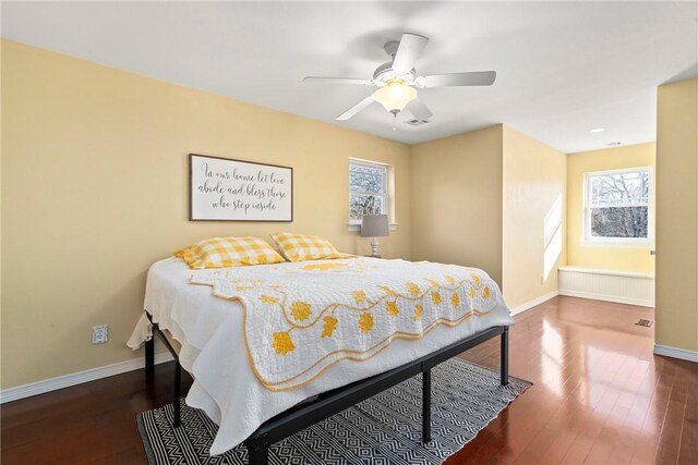 bedroom with dark wood-type flooring, radiator heating unit, and ceiling fan