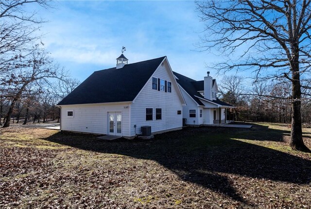 view of side of home with central AC and french doors