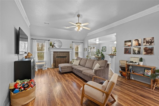 living room featuring lofted ceiling, crown molding, wood-type flooring, a textured ceiling, and ceiling fan