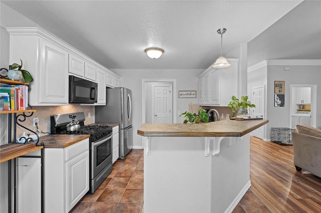 kitchen with stainless steel appliances, separate washer and dryer, white cabinets, and decorative light fixtures