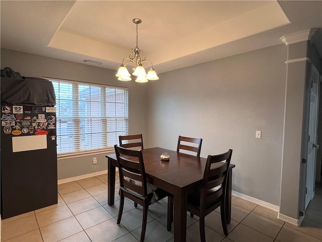 dining area featuring tile patterned flooring, a tray ceiling, and an inviting chandelier