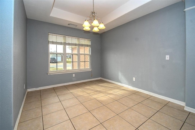 spare room featuring a raised ceiling, a notable chandelier, baseboards, and visible vents