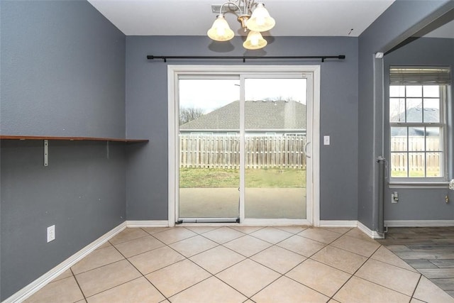 interior space featuring a healthy amount of sunlight, baseboards, and an inviting chandelier