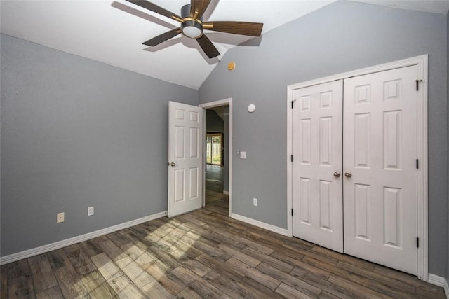 unfurnished bedroom with lofted ceiling, baseboards, dark wood finished floors, a ceiling fan, and a closet