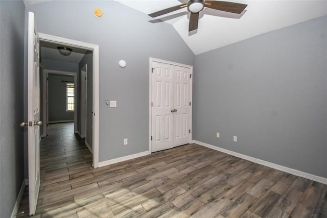 unfurnished bedroom featuring a closet, wood finished floors, lofted ceiling, baseboards, and ceiling fan