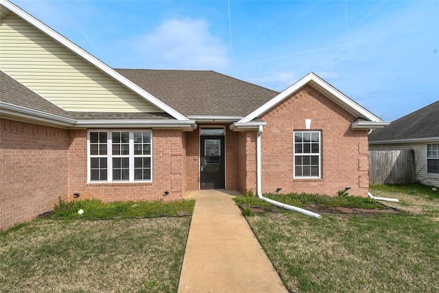 ranch-style home featuring a front lawn, brick siding, and roof with shingles