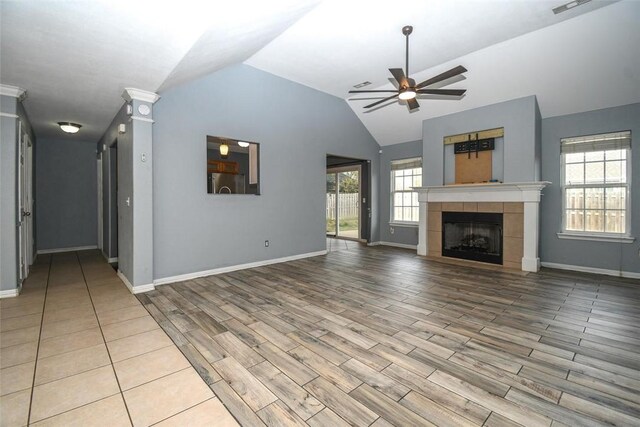 unfurnished living room with a ceiling fan, a fireplace, wood finished floors, lofted ceiling, and baseboards