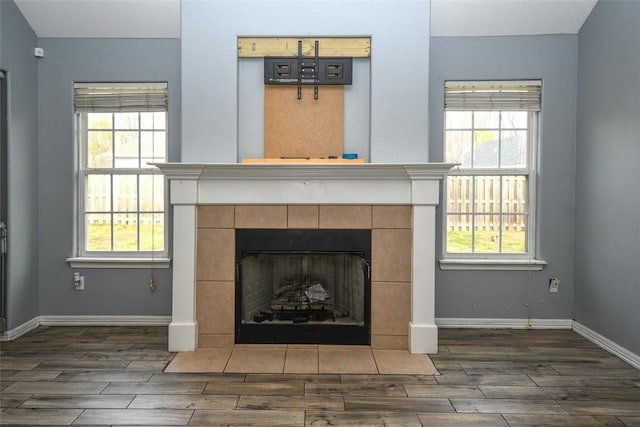 interior details with a tiled fireplace, wood finish floors, and baseboards