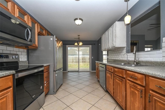 kitchen featuring hanging light fixtures, glass insert cabinets, appliances with stainless steel finishes, and light tile patterned floors