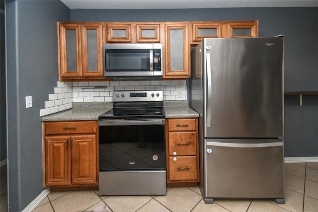 kitchen with light tile patterned floors, stainless steel appliances, tasteful backsplash, and brown cabinetry