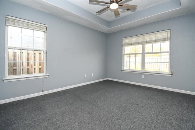 unfurnished room featuring a raised ceiling, baseboards, and a healthy amount of sunlight