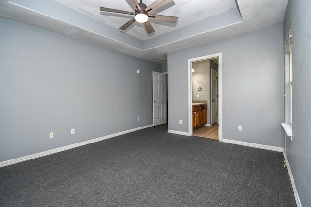 unfurnished bedroom featuring a raised ceiling, carpet floors, connected bathroom, and baseboards