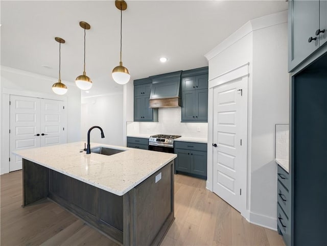 kitchen featuring sink, light stone counters, a center island with sink, custom range hood, and pendant lighting