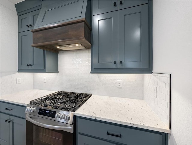 kitchen with tasteful backsplash, custom exhaust hood, light stone countertops, and stainless steel range with gas stovetop