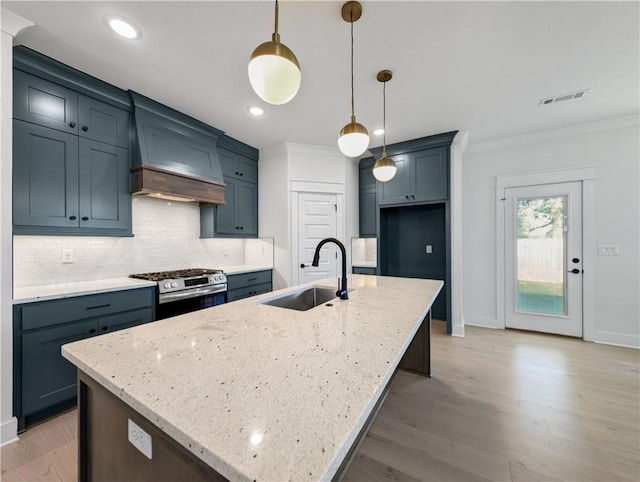 kitchen featuring pendant lighting, an island with sink, gas stove, and light stone counters