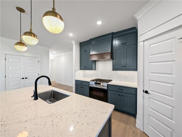 kitchen with sink, crown molding, light stone counters, gas stove, and decorative light fixtures