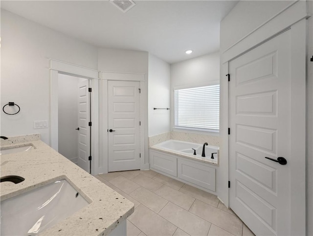 bathroom featuring vanity, a bath, and tile patterned flooring