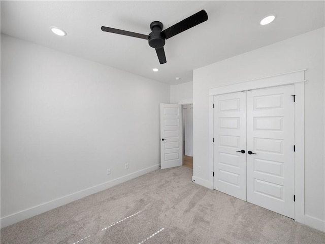 unfurnished bedroom featuring ceiling fan, light colored carpet, and a closet