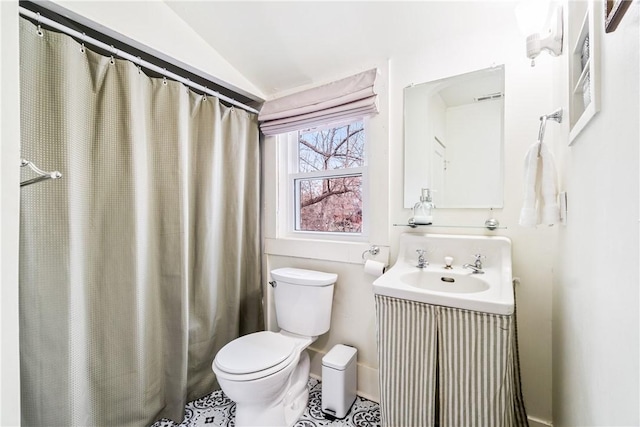 bathroom featuring sink, curtained shower, vaulted ceiling, and toilet