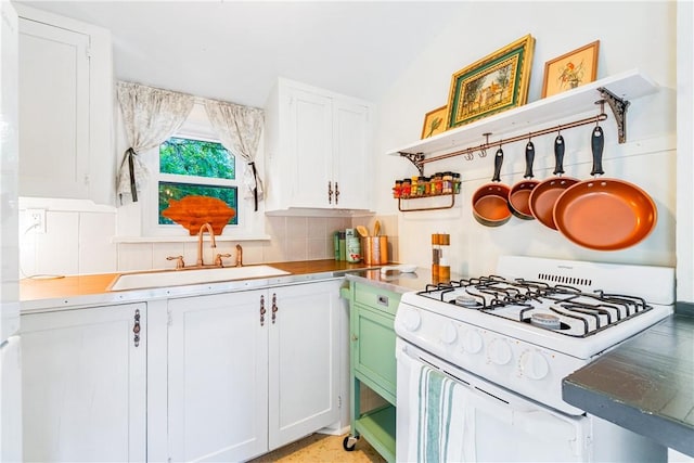 kitchen featuring tasteful backsplash, sink, gas range gas stove, and white cabinets