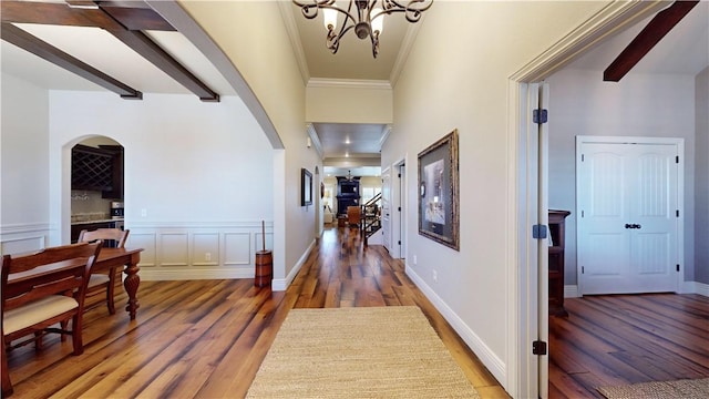 hallway featuring ornamental molding, dark hardwood / wood-style flooring, beam ceiling, and a notable chandelier