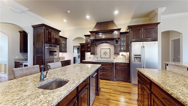 kitchen with sink, light stone counters, tasteful backsplash, light hardwood / wood-style flooring, and stainless steel appliances