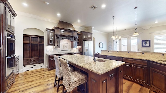 kitchen featuring appliances with stainless steel finishes, sink, a kitchen breakfast bar, hanging light fixtures, and a kitchen island with sink