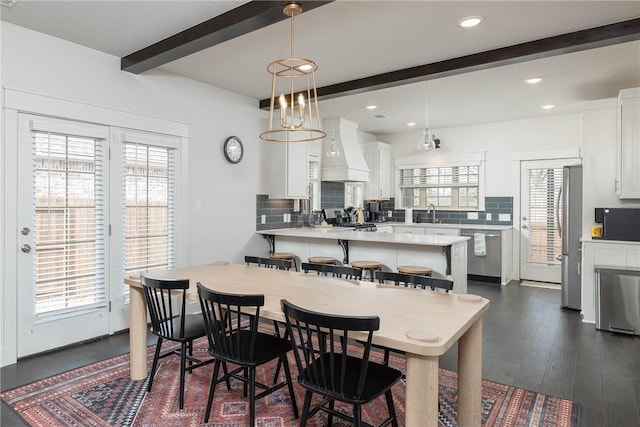 dining space featuring beamed ceiling, sink, and dark wood-type flooring