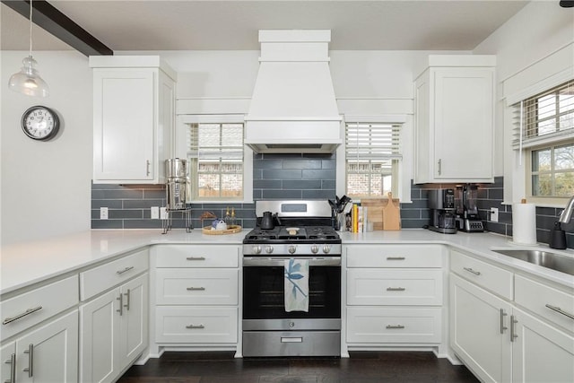 kitchen featuring premium range hood, sink, decorative light fixtures, stainless steel range with gas cooktop, and white cabinets