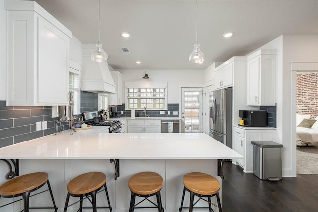 kitchen featuring white cabinetry, stainless steel appliances, and decorative light fixtures