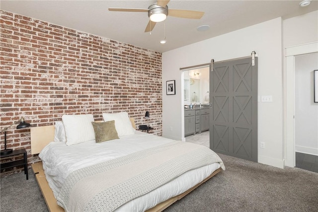 carpeted bedroom featuring brick wall, ensuite bathroom, a barn door, and ceiling fan