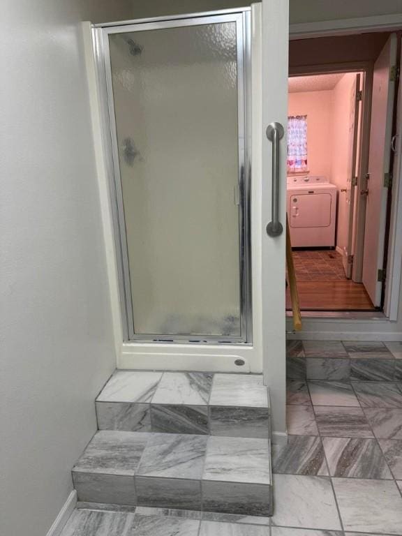 bathroom featuring washer / clothes dryer and an enclosed shower