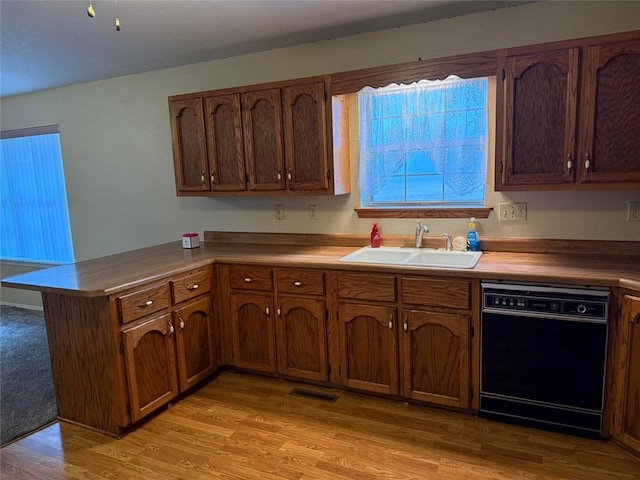 kitchen with light hardwood / wood-style floors, dishwasher, sink, and kitchen peninsula