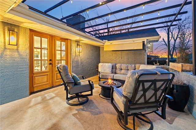 patio terrace at dusk with a pergola, a fire pit, and french doors