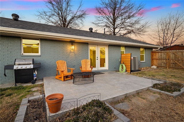 back house at dusk featuring a patio area, a fire pit, and central air condition unit