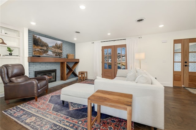 living room with dark wood-type flooring, a fireplace, built in features, and french doors