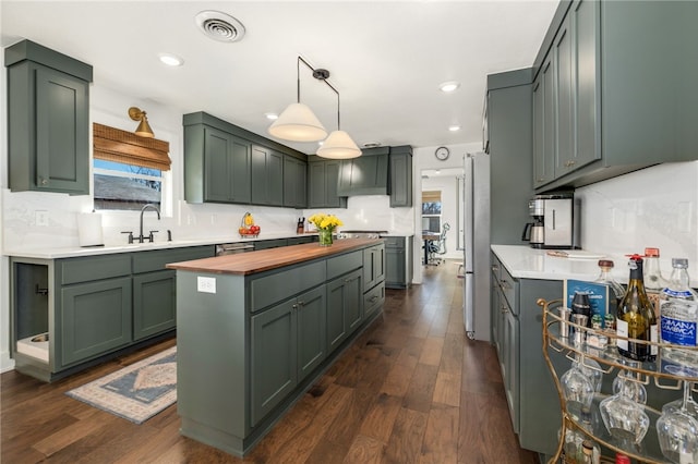 kitchen featuring dark wood-type flooring, green cabinetry, stainless steel appliances, and decorative light fixtures