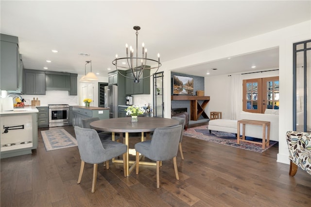 dining area with french doors, sink, an inviting chandelier, a brick fireplace, and dark hardwood / wood-style floors