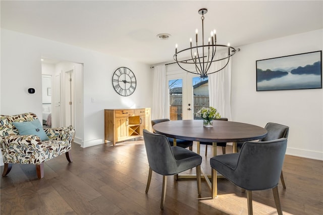 dining space featuring dark wood-type flooring, a notable chandelier, and french doors