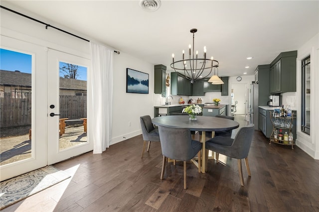 dining area featuring dark wood-type flooring, sink, an inviting chandelier, and french doors