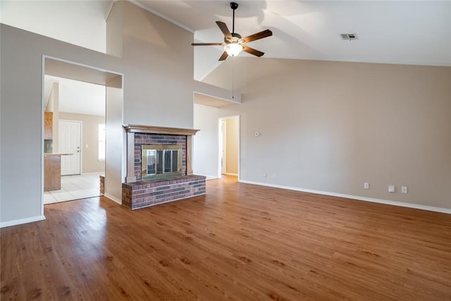 unfurnished living room featuring ceiling fan, high vaulted ceiling, a brick fireplace, and light wood-type flooring