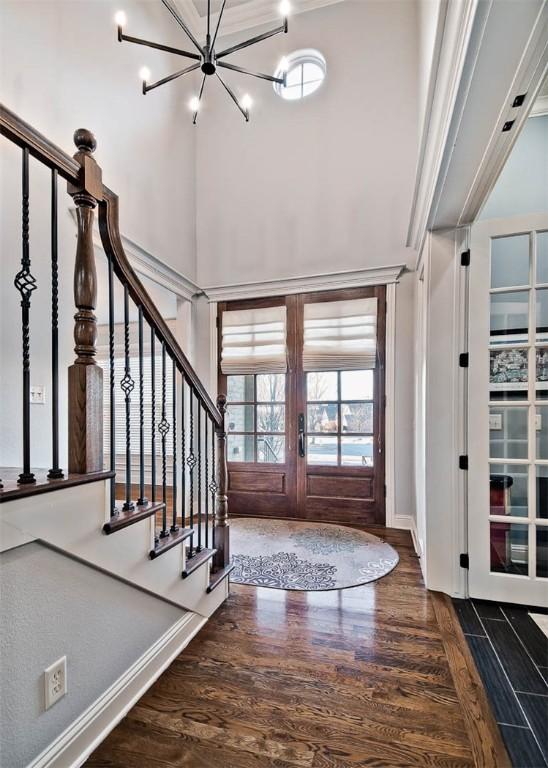 entryway featuring french doors, dark hardwood / wood-style floors, a chandelier, and a high ceiling