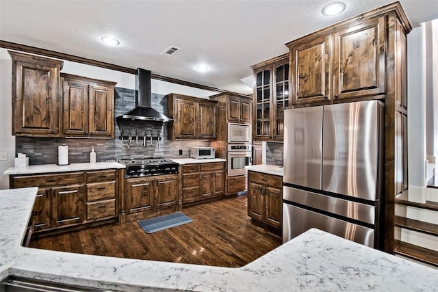 kitchen featuring wall chimney exhaust hood, stainless steel appliances, dark hardwood / wood-style flooring, and backsplash